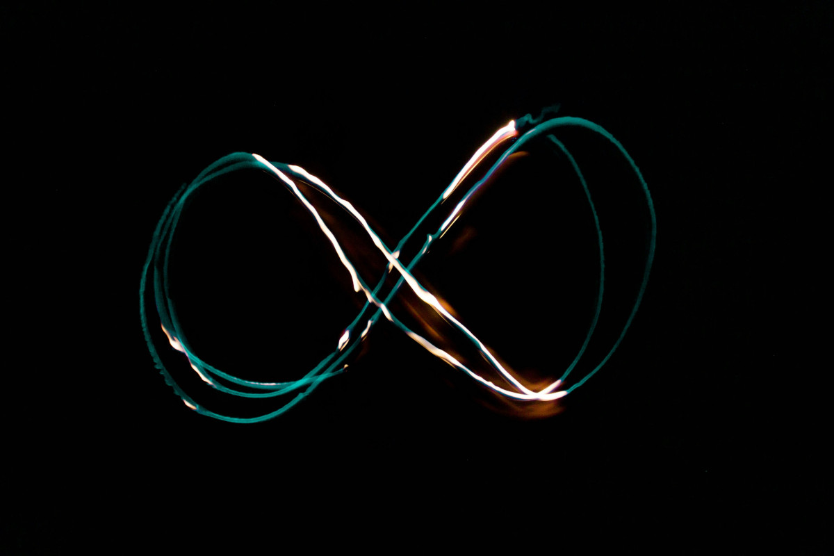 An abstract image of an infinity loop with a bright light at the end, creating a patterned effect. The colors are dark and moody, with the light being the only significant source of illumination. It has a glitch art vibe.