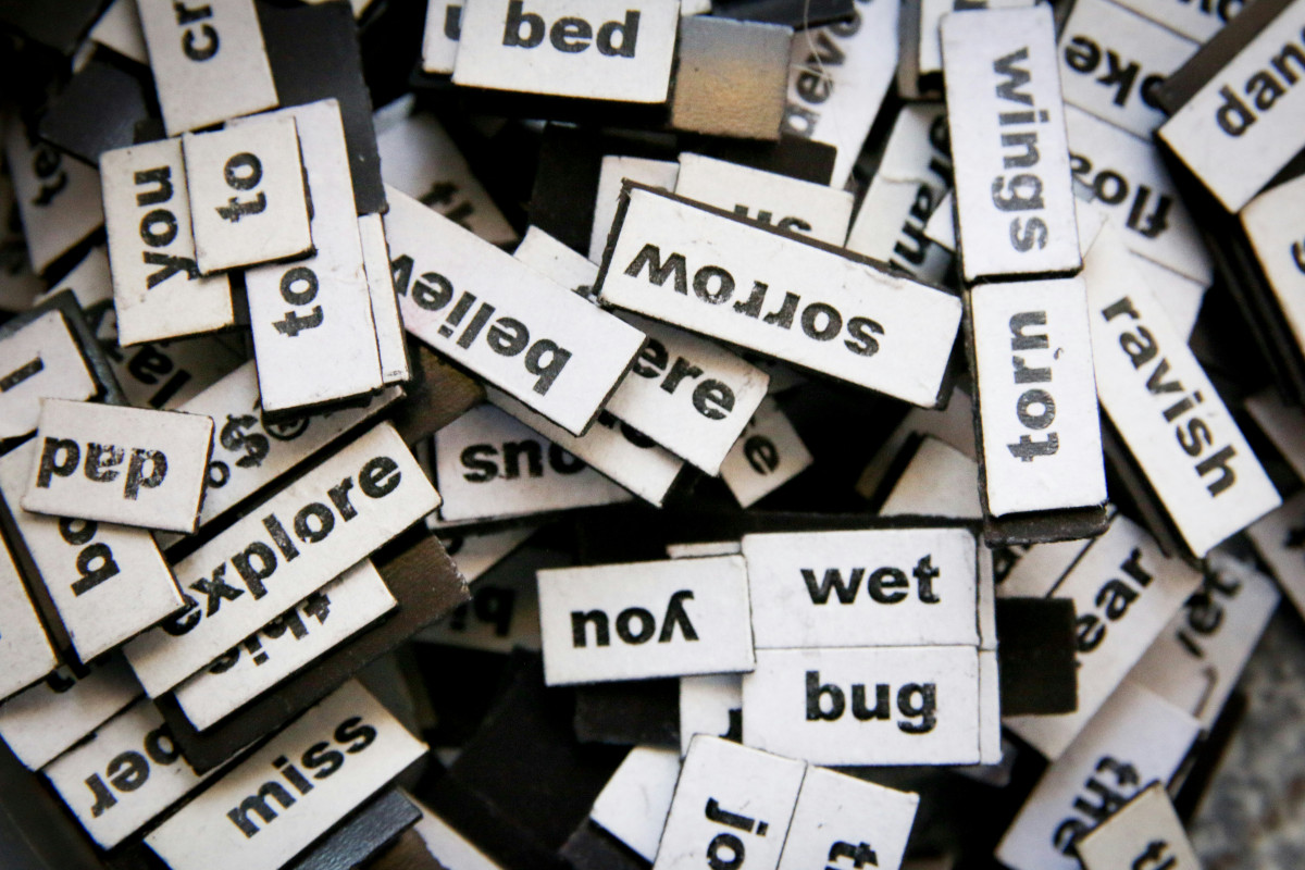 The image shows a collection of scrabble tiles with various words written on them. These words are likely used to create different phrases or sentences, as is typical in the game of Scrabble. Each tile has a single word printed on it, and these tiles appear to be arranged casually. The photograph is taken at an angle that captures the variety of letters available for use in this word-building activity. There are no people visible in the image.