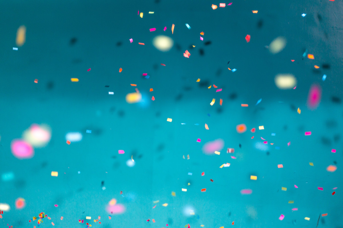 Selective focus photography of multicolored confetti against a blue background