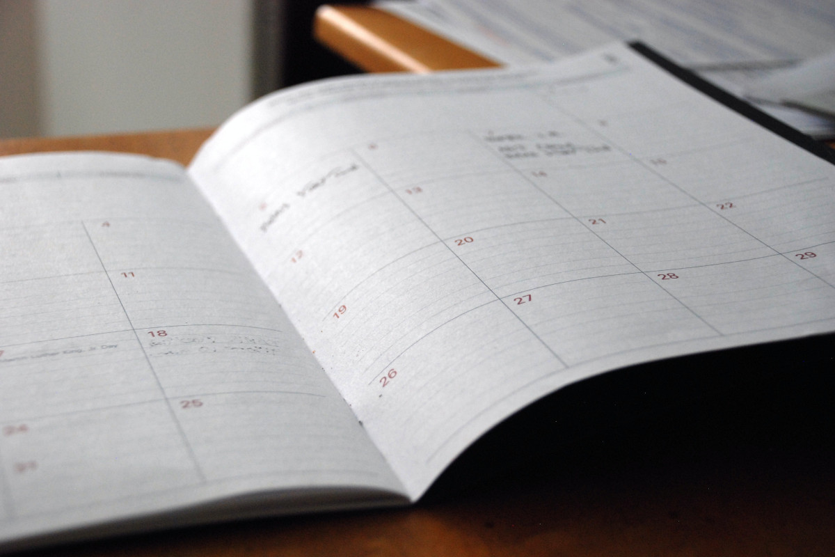 An planner, laying open on a desk. The planner has a month-to page view.