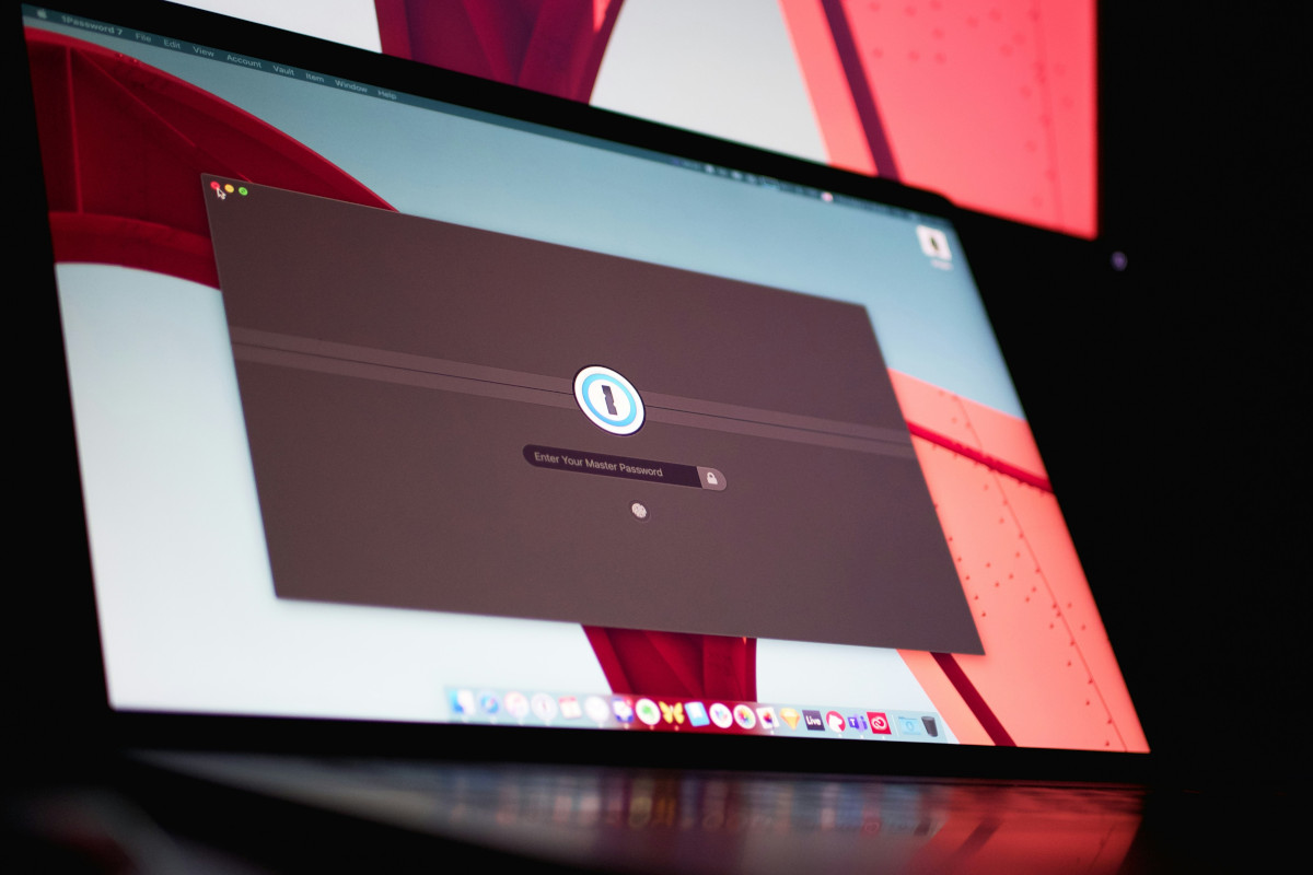 The image shows a desktop computer setup with a large monitor in the foreground. On the screen, there is a window open displaying what appears to be a user interface or software application with a login or sign-in page. The page has a prompt for entering credentials and a 'Next' button below it. In the background, behind the screen, there is a wall with a colourful pattern that includes red and white hues. There are no texts visible in the image, and the focus is on the computer setup rather than any additional context or background elements.
