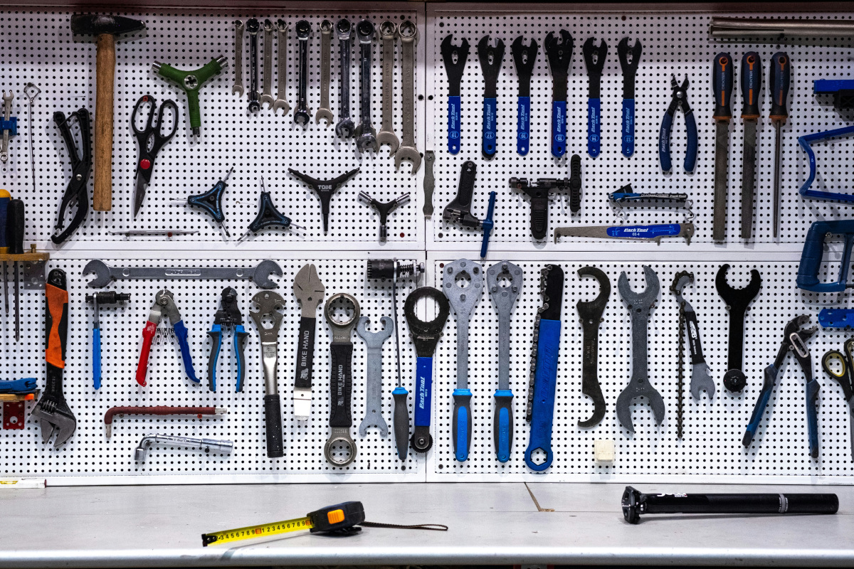 This is an image of a collection of tools organized in a grid on pegboard. The tools vary in size and type, including pliers, wrenches, screwdrivers, and possibly other small hand tools. There's a variety of shapes and sizes represented, suggesting that the collection is meant for diverse tasks. The background is neutral, likely a wall or similar backdrop, which makes the colors and details of the tools stand out clearly. The tools are all in good condition and appear to be organized by type and size. There's no text visible in this image. 