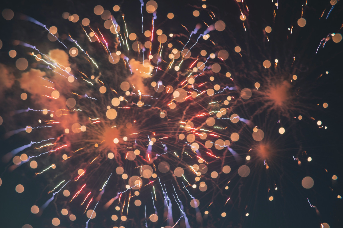 The image captures a vibrant night scene featuring fireworks. A multitude of fireworks bursts in the sky, their colors ranging from bright red and yellow to deep blue. The shapes of the fireworks vary, with some appearing as stars while others have more defined forms, possibly due to their proximity to the camera. The fireworks are set against a dark background, which contrasts sharply with the luminous bursts. The overall composition of the image, with the fireworks centrally positioned and spread across the frame, gives a sense of festivity and celebration.